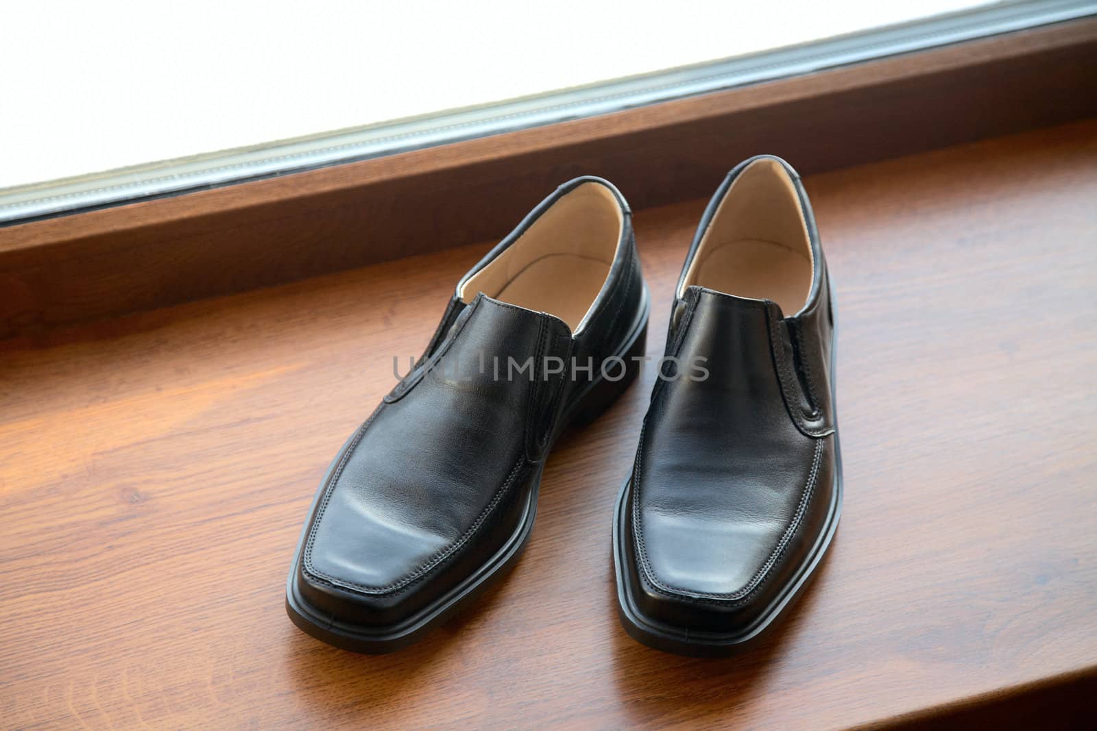 Black man's shoes stand on a window sill