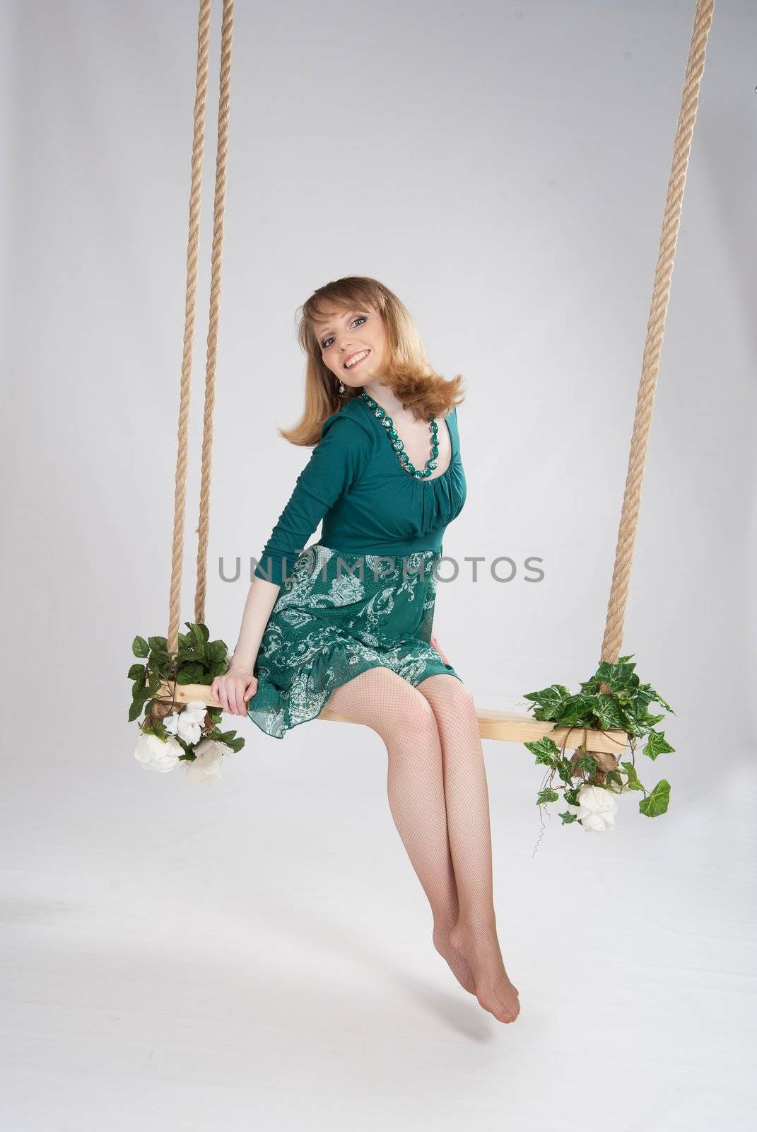 beautiful woman in a green dress on a swing