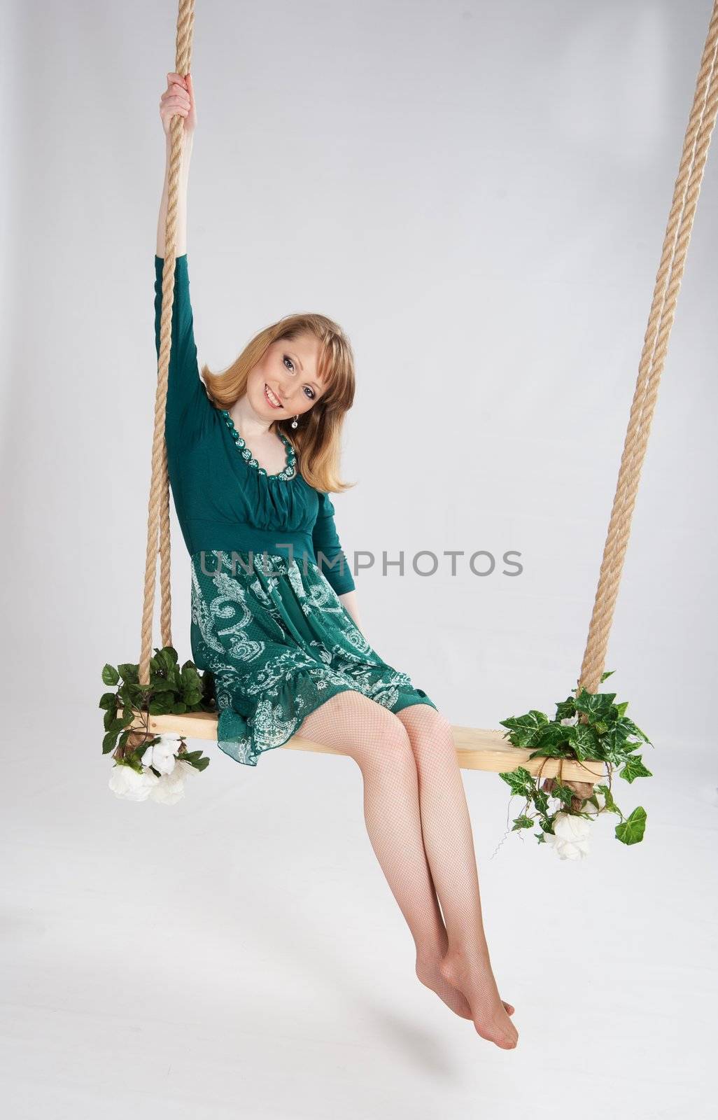 beautiful woman in a green dress on a swing