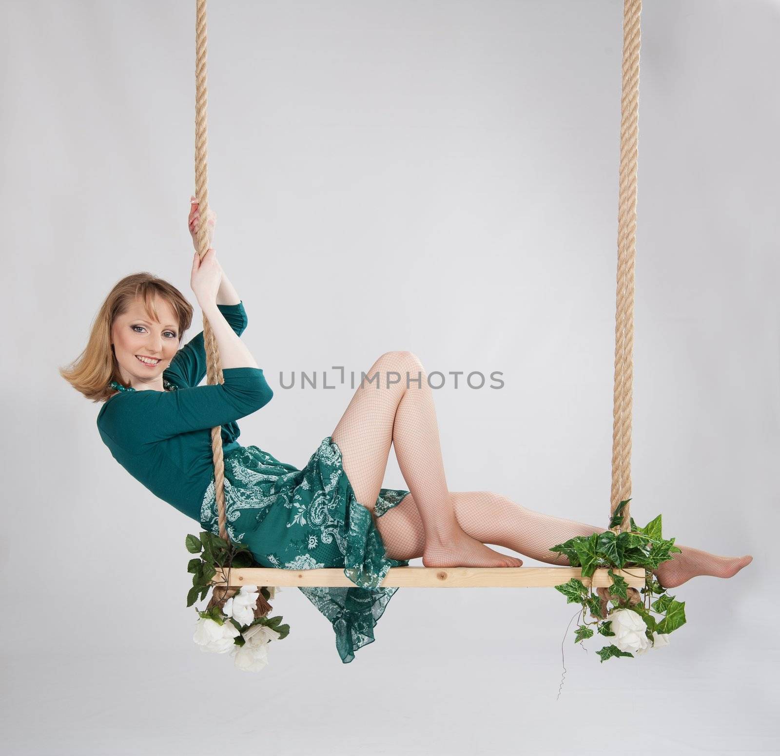 beautiful woman in a green dress on a swing