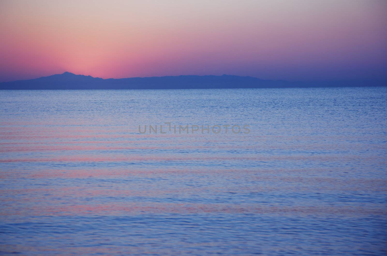 View on serene beach with sunrise behind the mountains. Natural light and colors