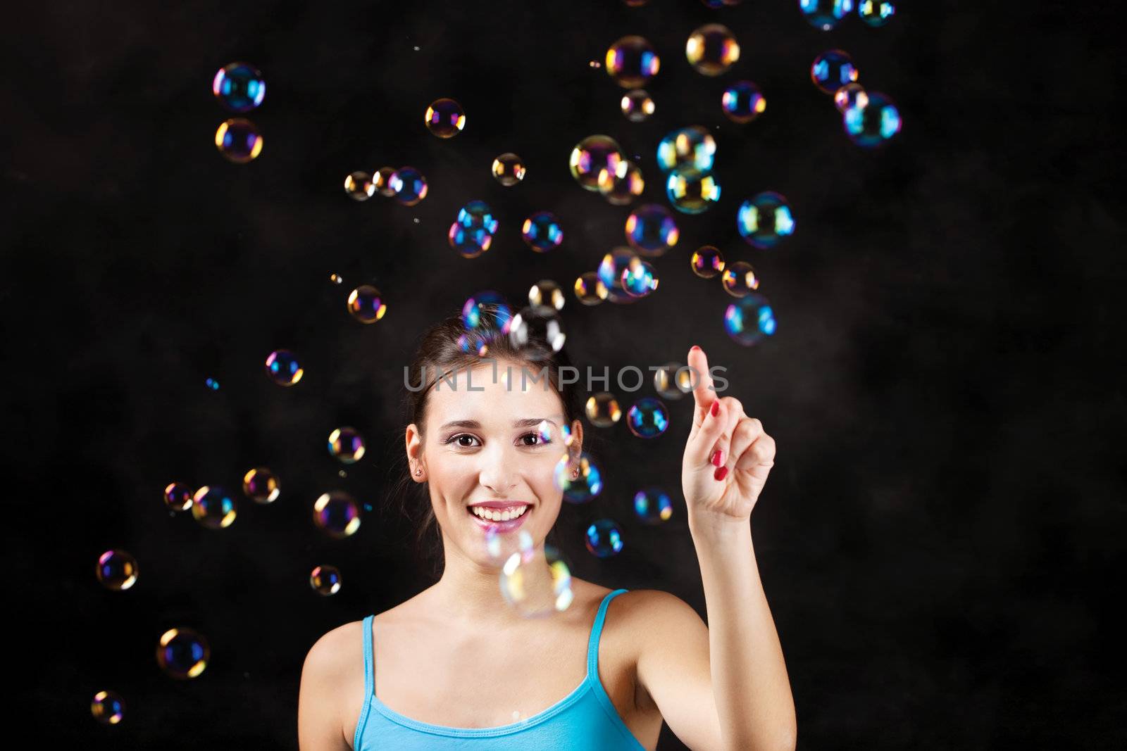 Happy girl and soap bubbles on the black background