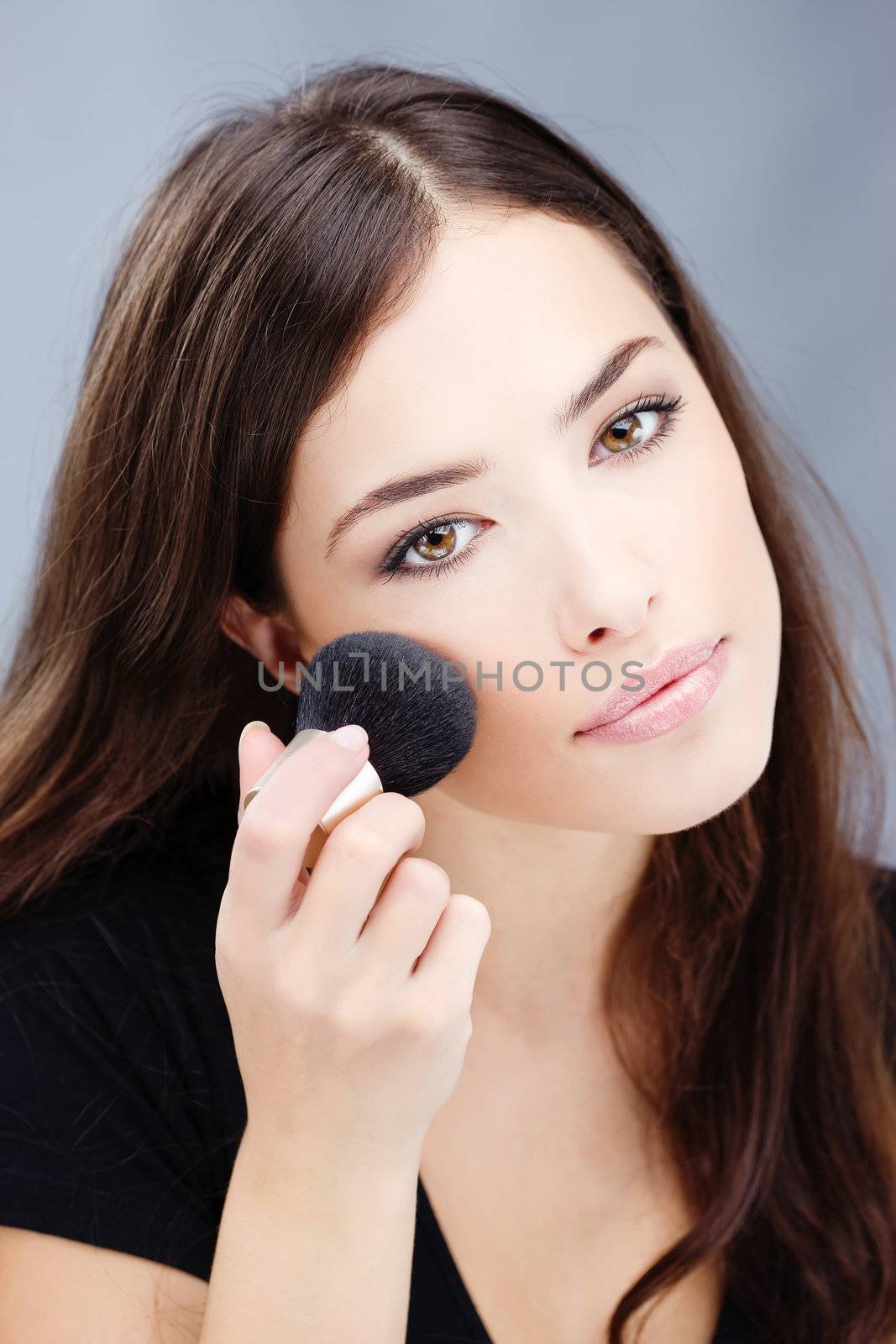 woman doing makeup with powder brush