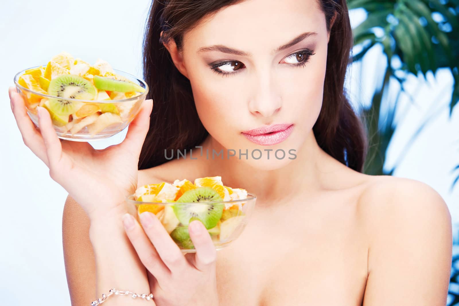 pretty brunette girl with two bowl full of fruit in her hands