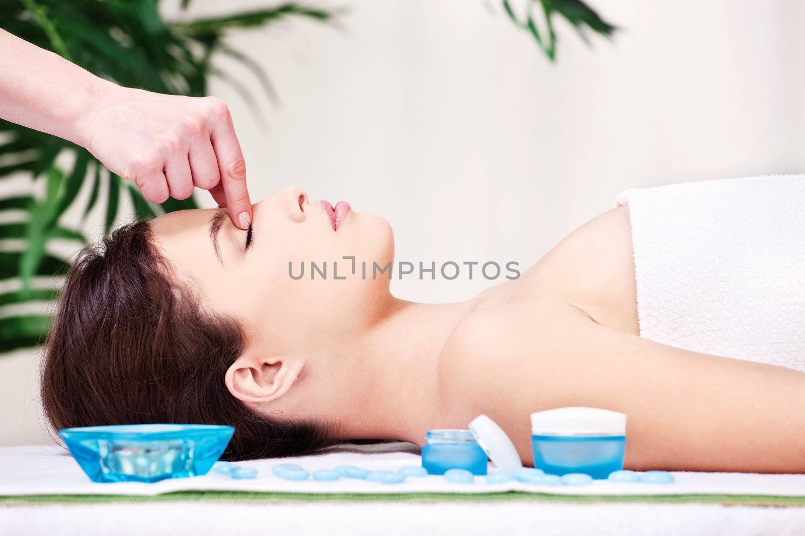 Pretty woman on forehead massage treatment in spa salon