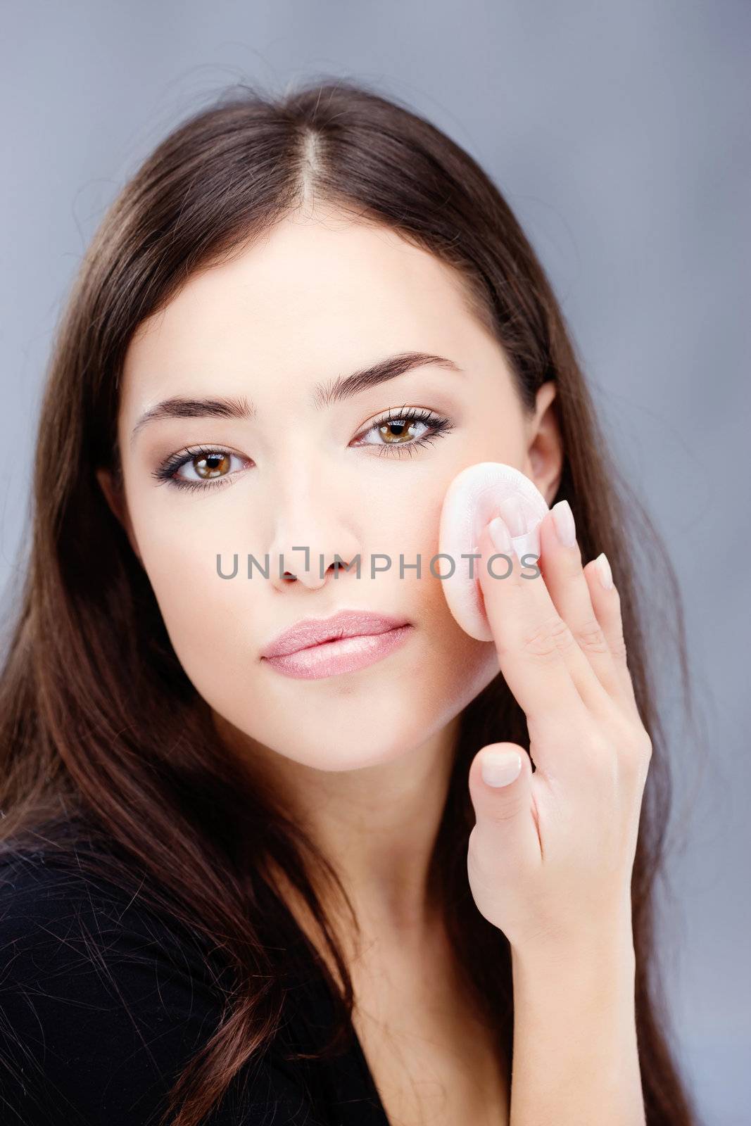pretty woman applying make up with cosmetic sponge