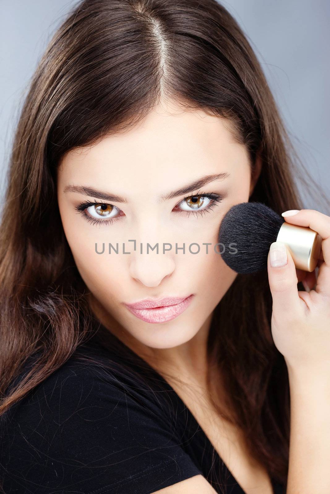 young pretty girl doing makeup with powder brush