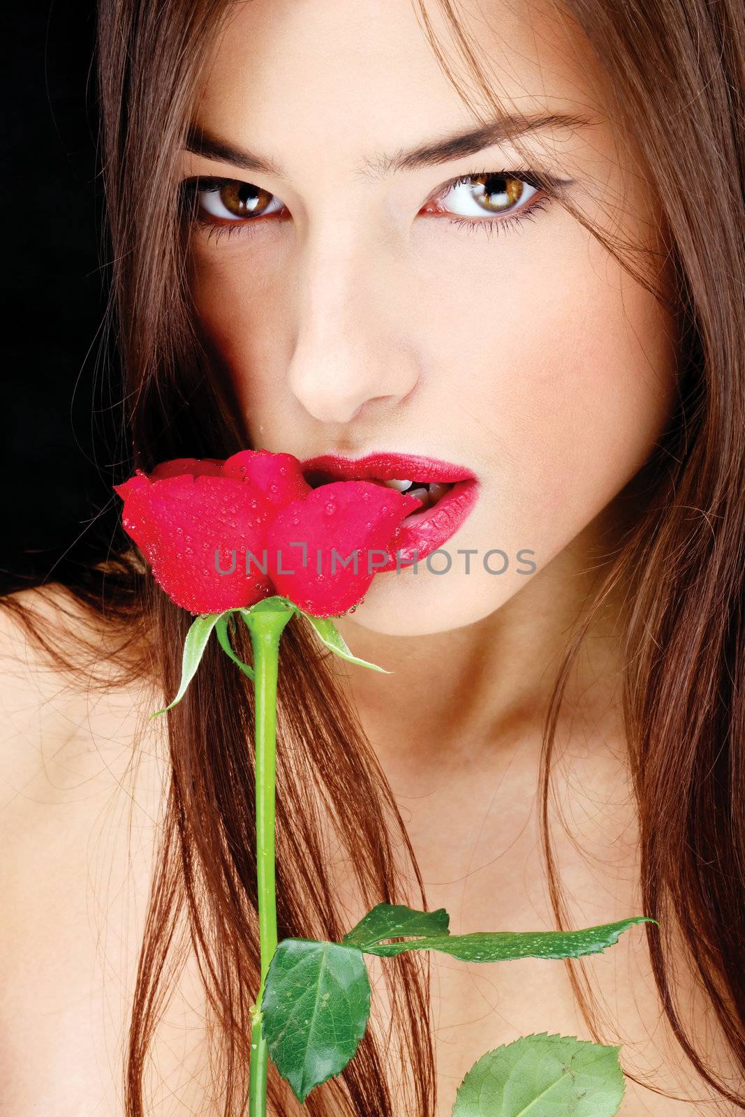 Pretty woman with long hair biting red rose