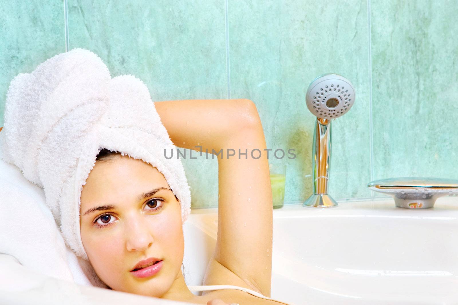 Young woman with white towel on head in the bathtub