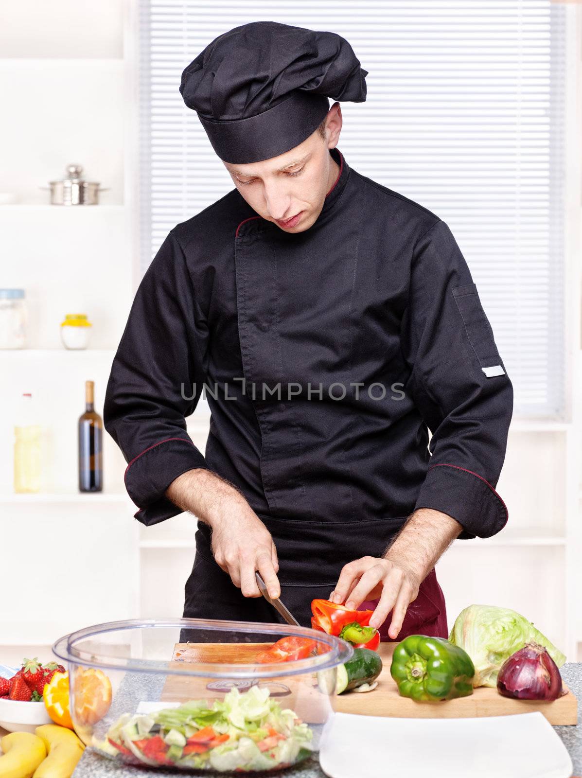 chef cutting bell peppers in kitchen by imarin