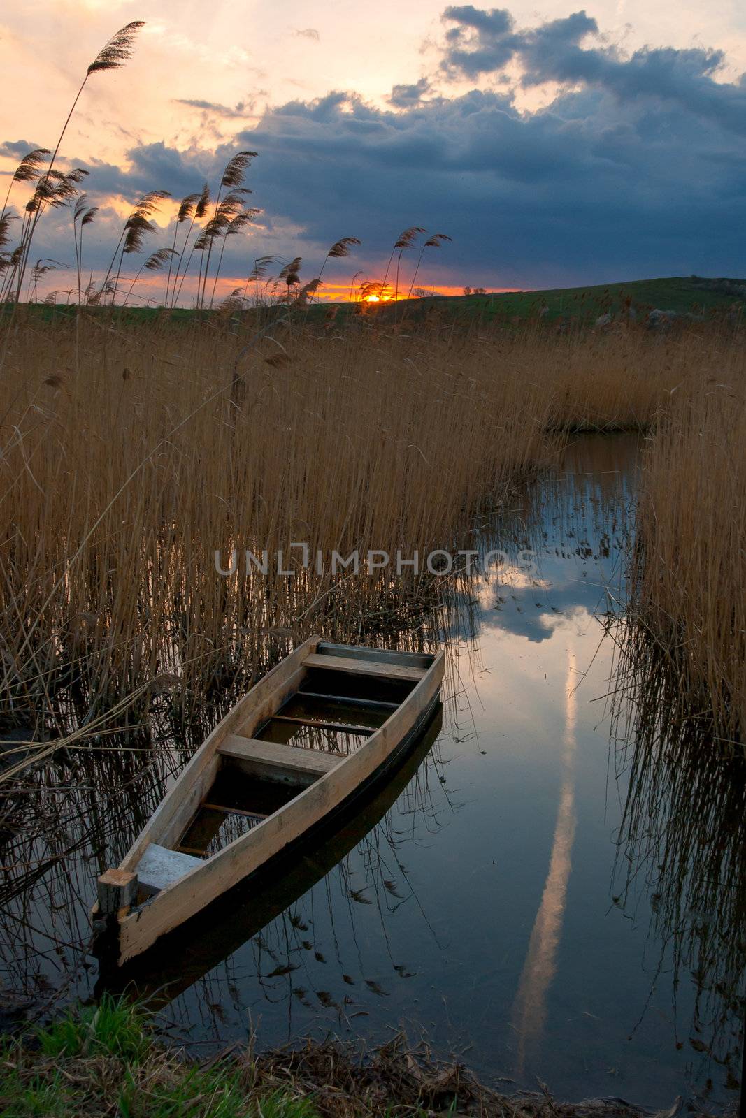 The lonely boat on the river, evenig sky with sunrise and clouds on background, outdoors