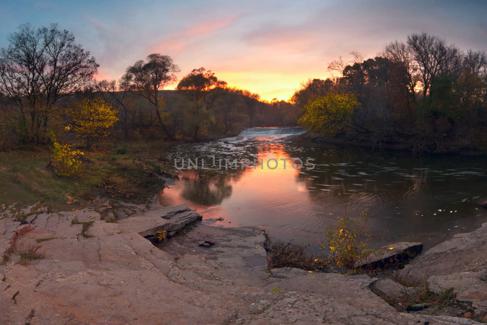 Colorful sunrise over the river with bright clouds. Autumn landscape