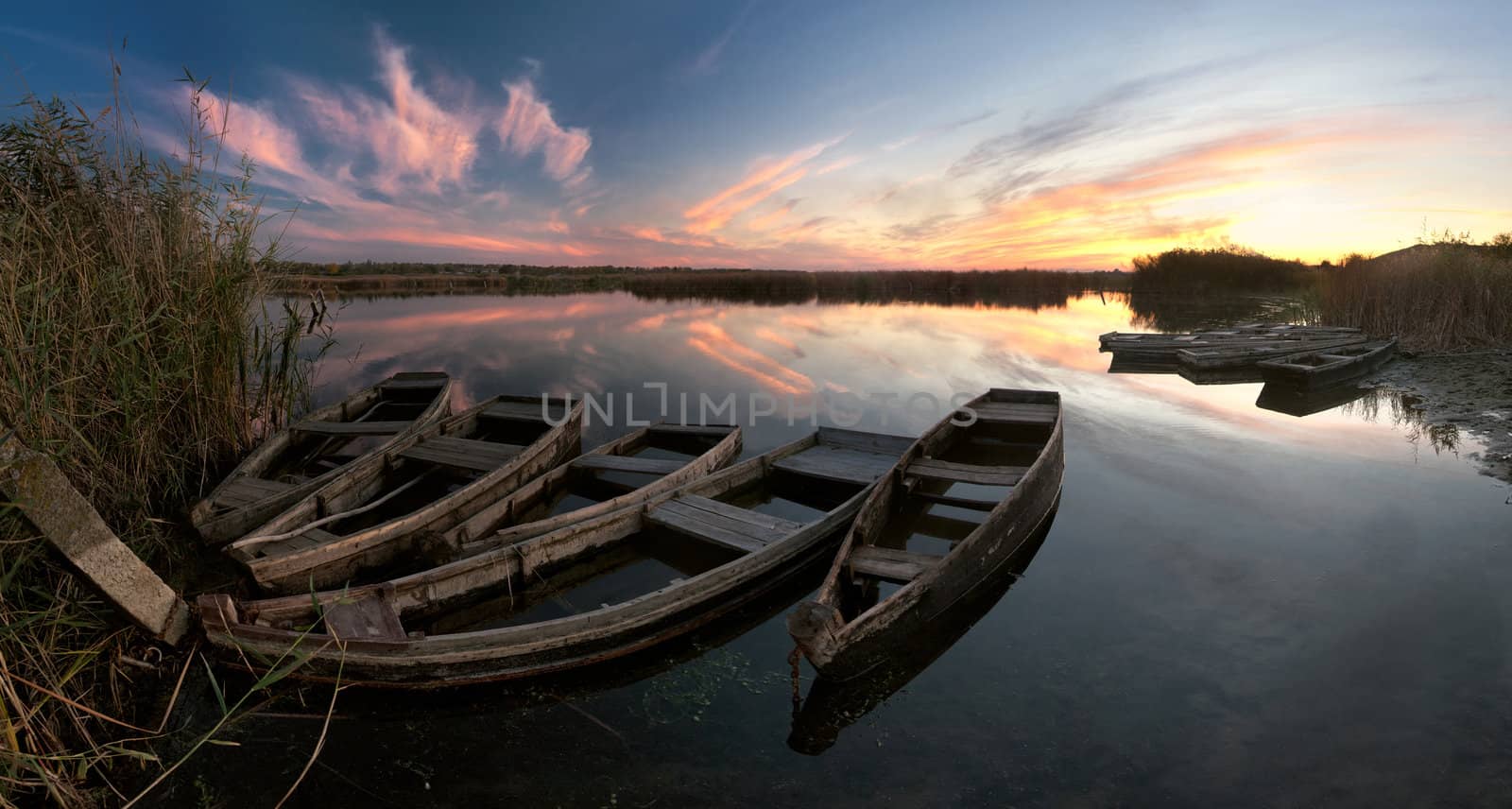 Evening colorful landscape with boats on the river and majestic sky reflection in the water