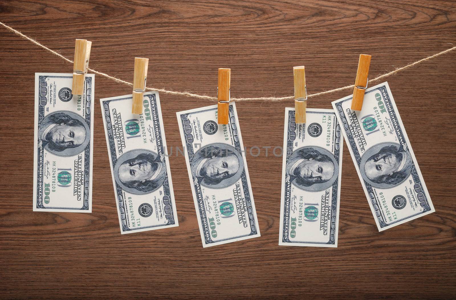 US Dollars Hanging on Rope with Clothespins on wooden background