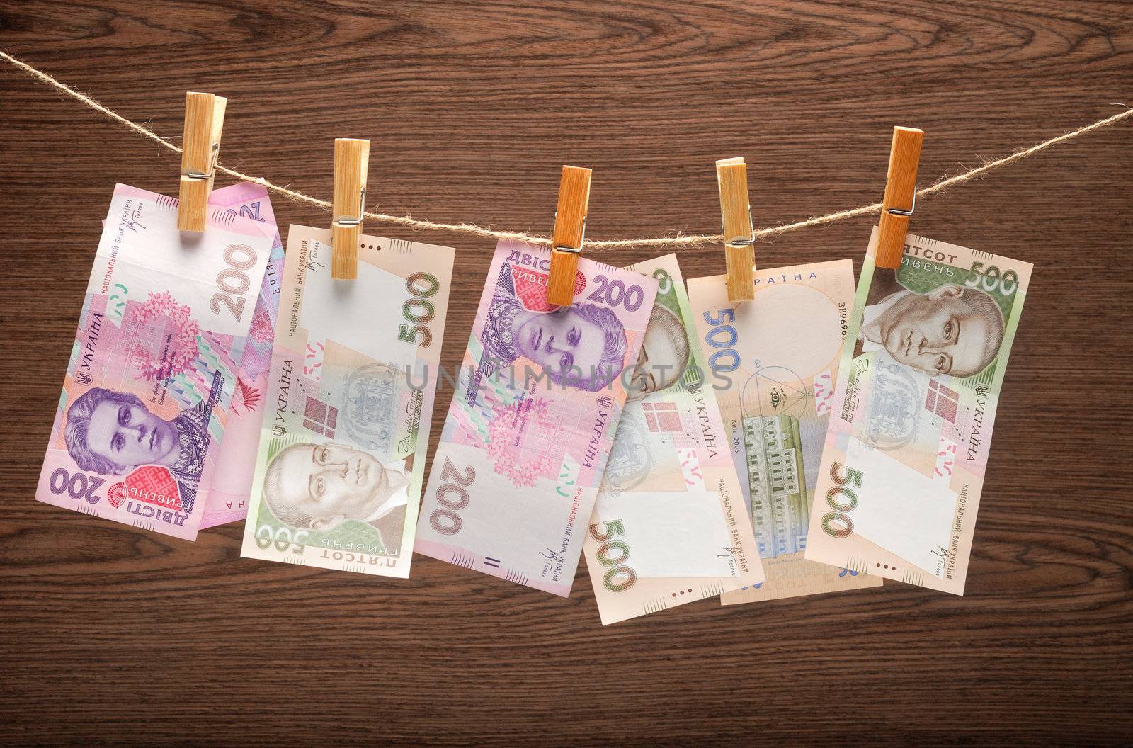 Ukrainian grivnas Hanging on Rope with Clothespins on wooden background