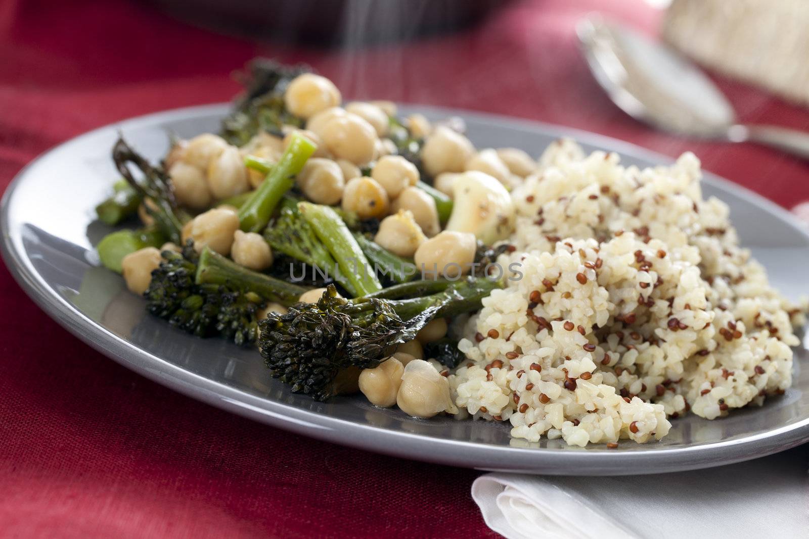 Steaming plate of broccoli and chickpeas served with bulgar and quinoa mix.