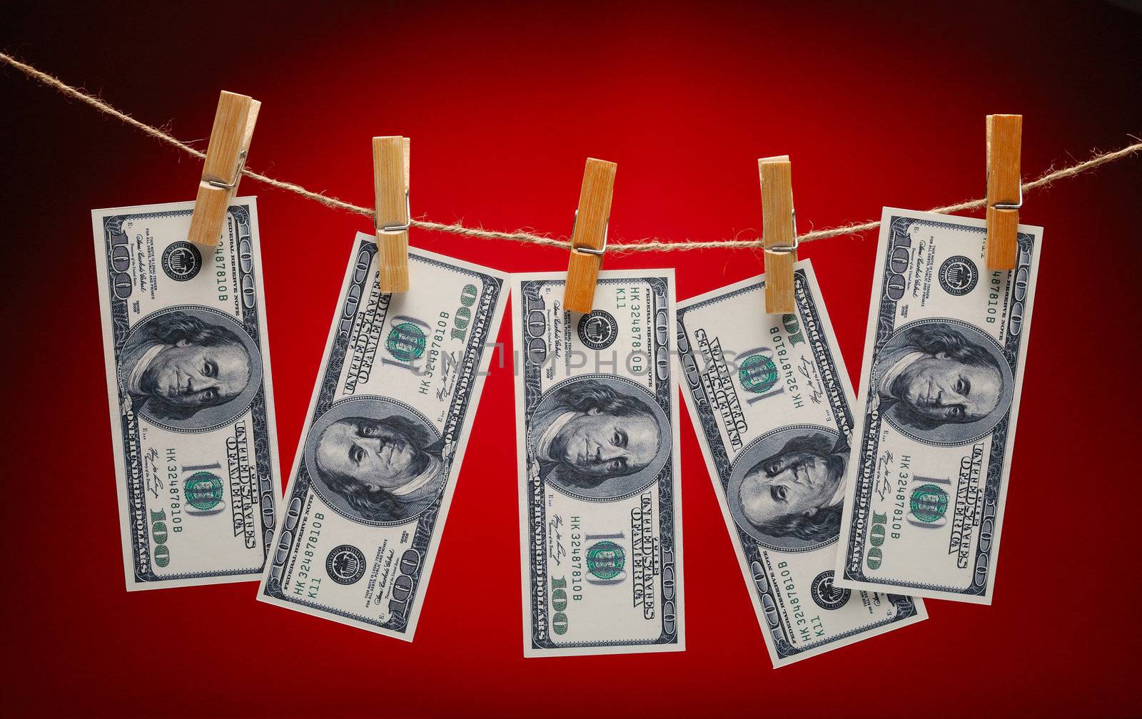 US Dollars Hanging on Rope with Clothespins on red background
