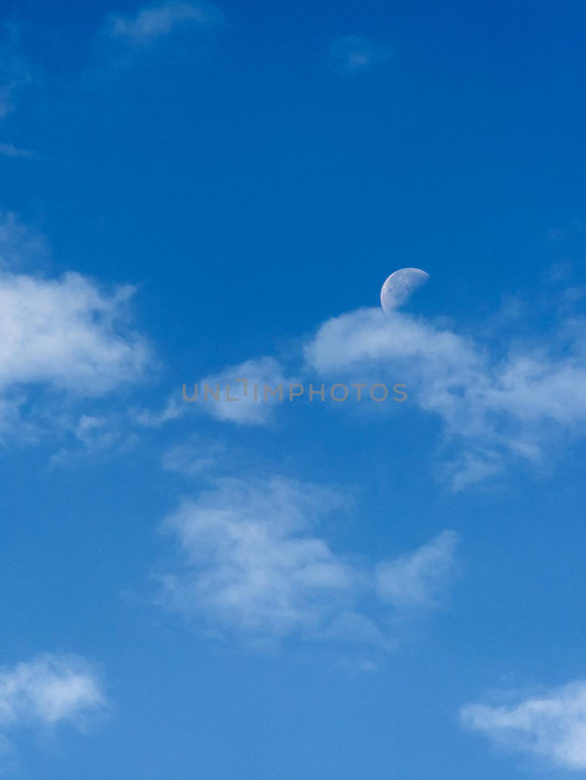 Bright blue morning sky with the half moon and clouds