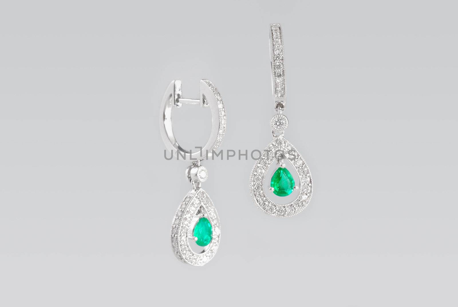 Two silver earrings with diamonds over white background