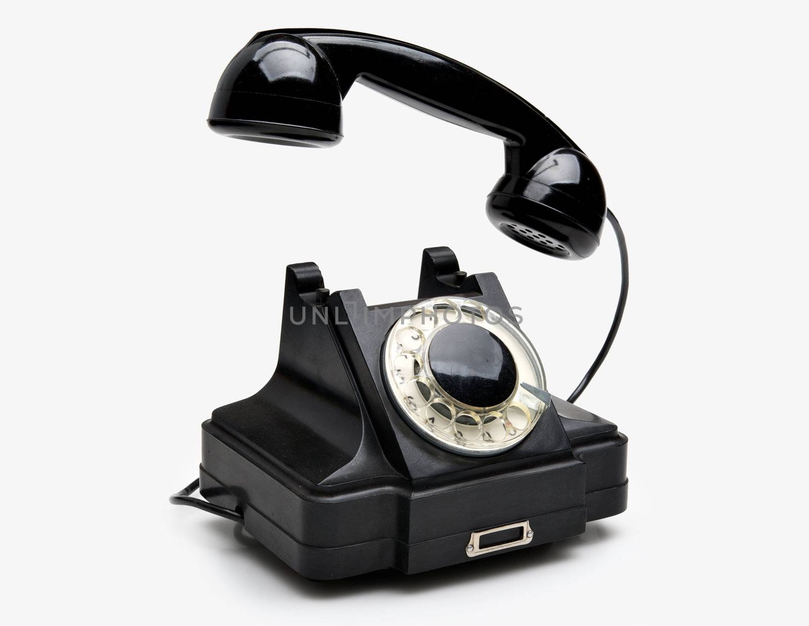 Old black vintage rotary style telephone isolated over a white background