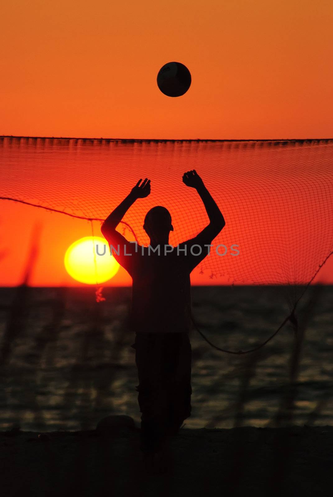 Family playing beach volleyball in the sunset