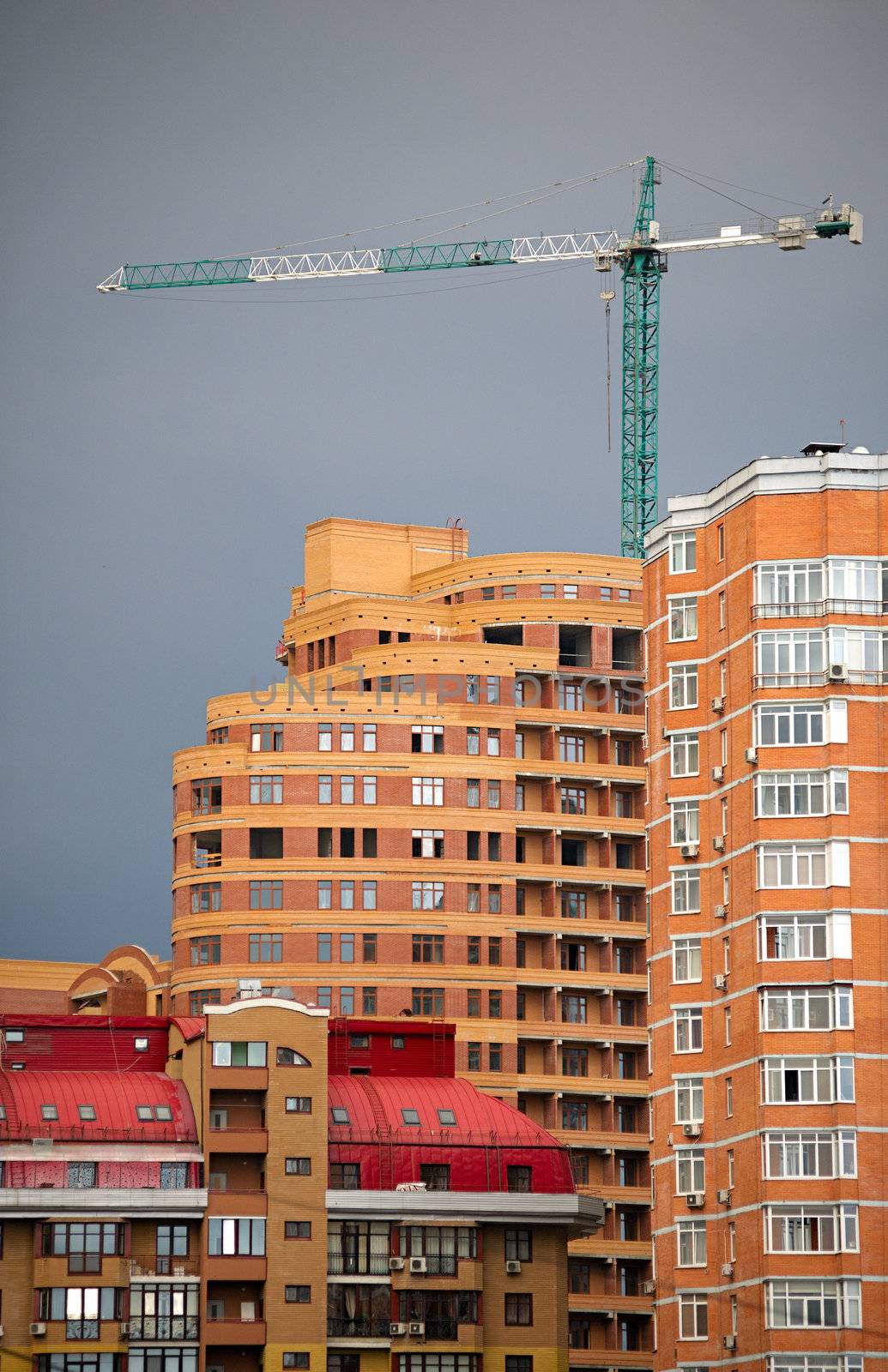 Architectural abstract of modern multi apartments building and hoisting crane in a sunset (recent development)