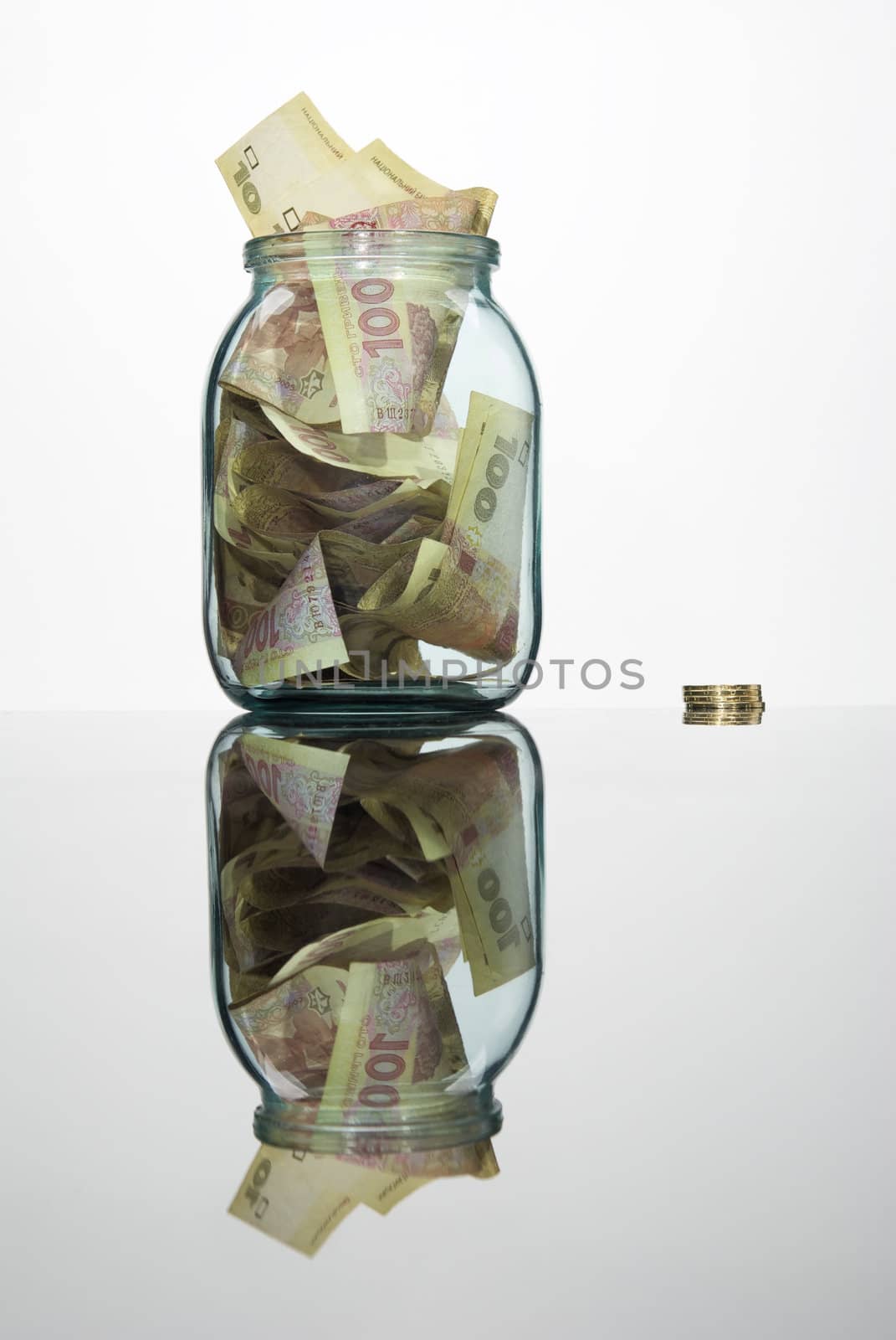 Glass jar full of hundreds of grivnas isolated on white background