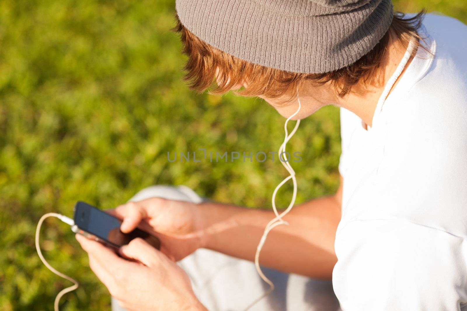 young handsome man consulting phone outdoors by Lcrespi