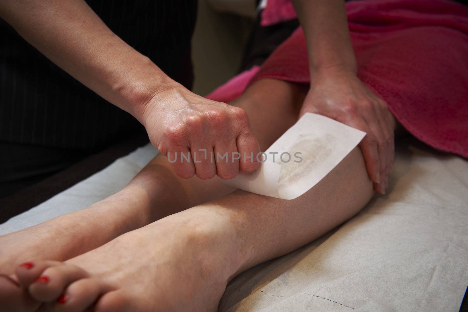 beautician applying wax to females leg to remove hair