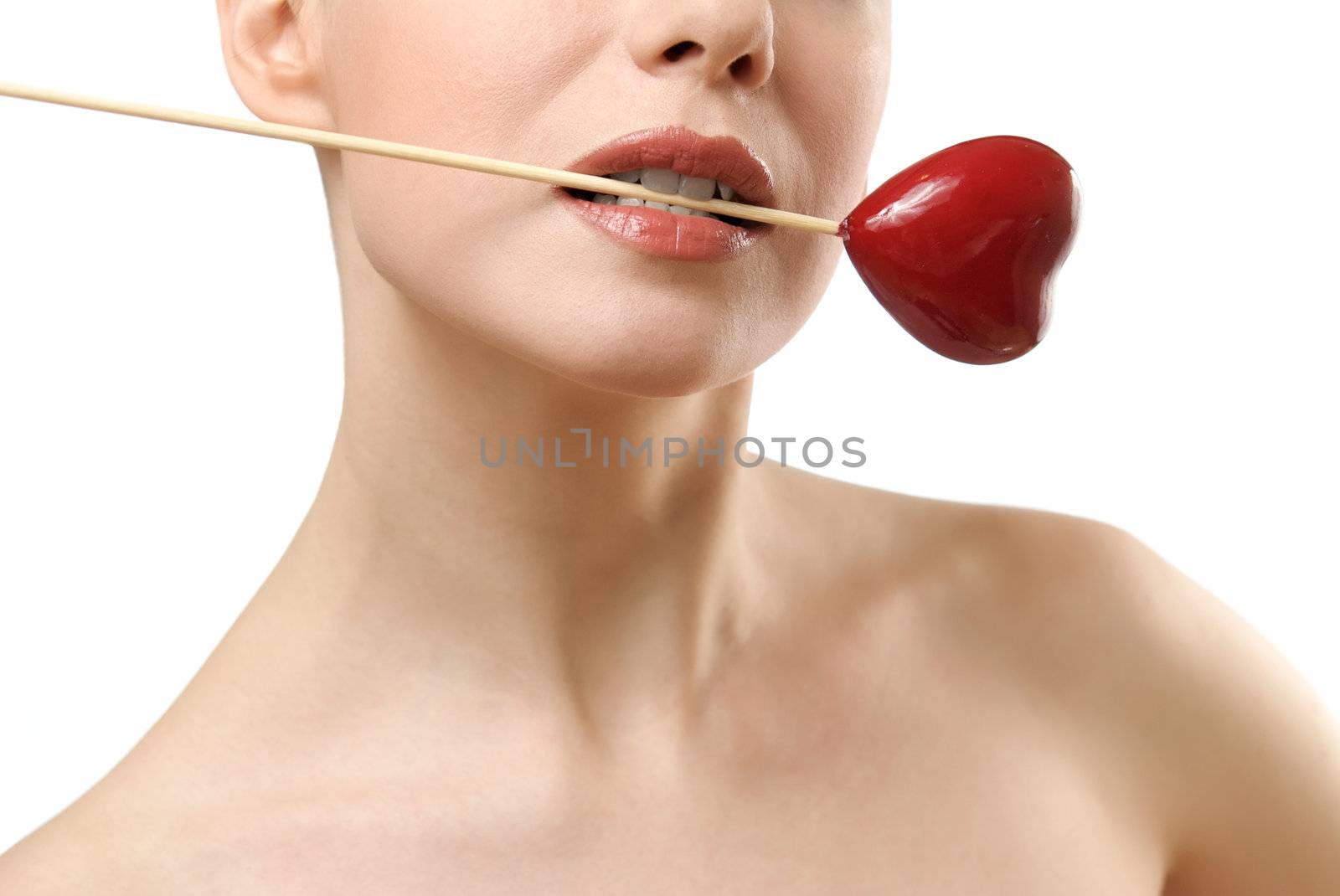 Beautiful woman holding red heart in her teeth. Face closeup. Isolated on white background
