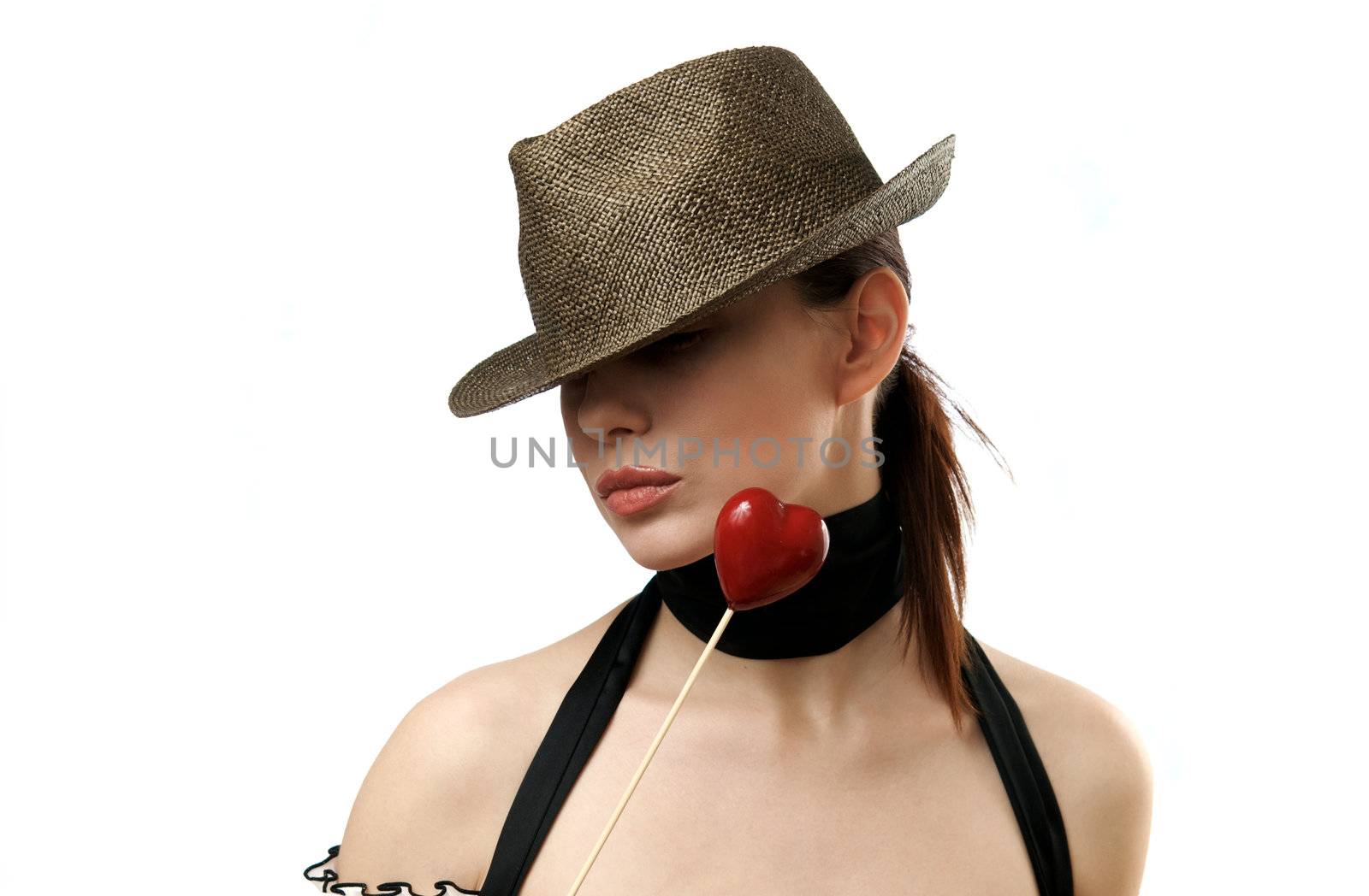 Young woman wearing hat holding heart shaped candy. Isolated on white background