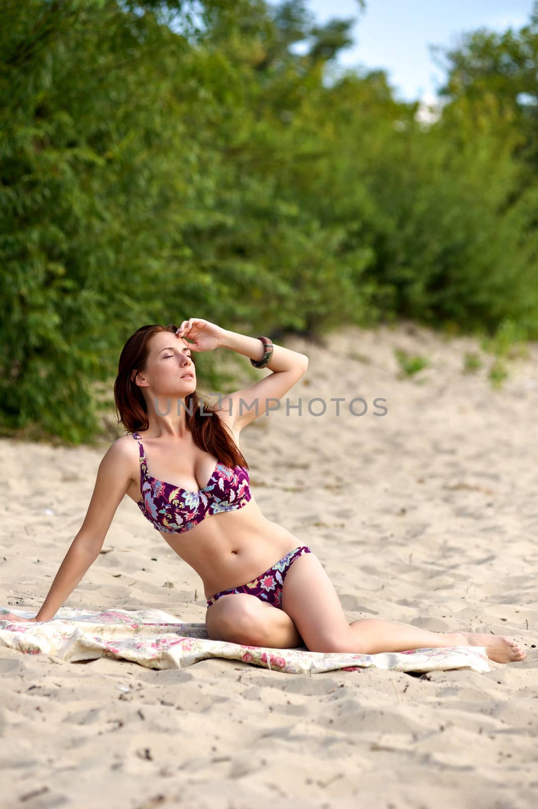 Young woman sunbathing on the beach in bikini alone