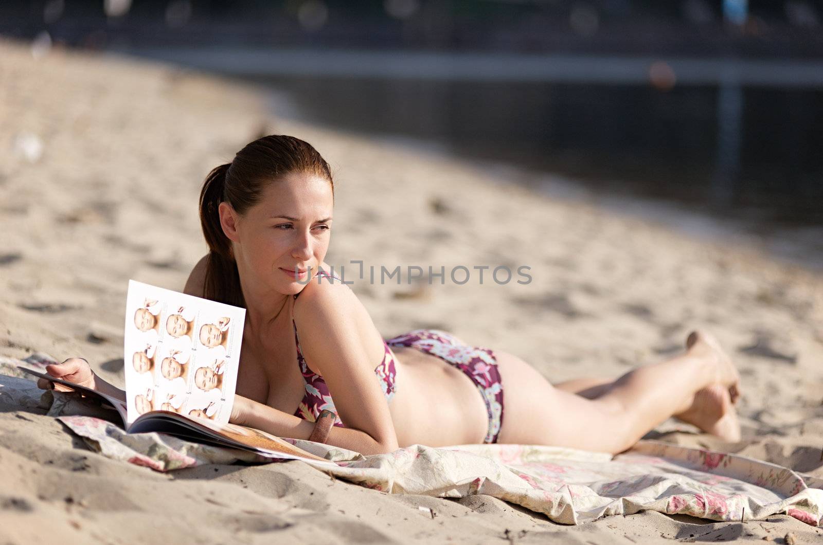 Young beautiful woman reading magazine at the beach