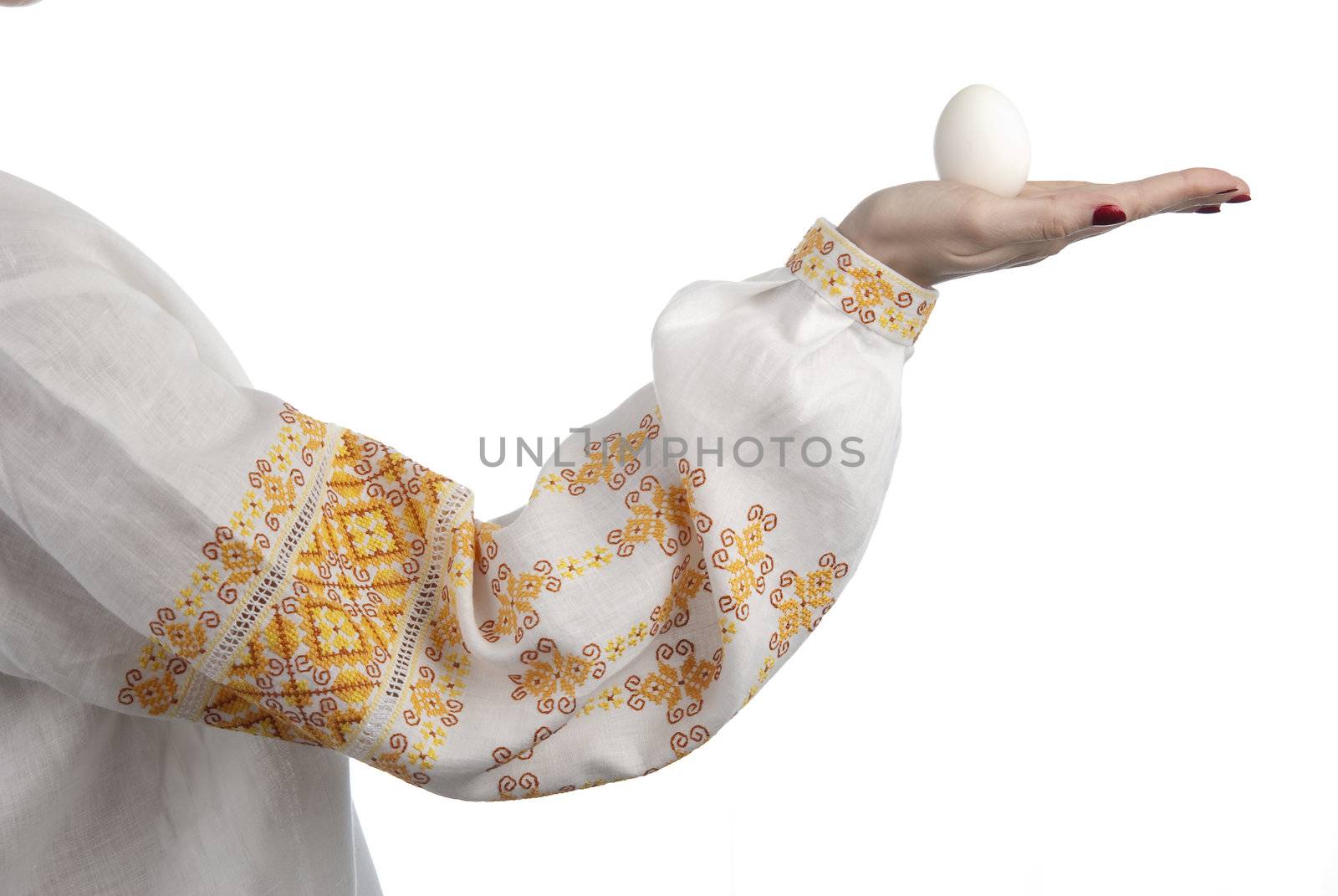 Woman's hand holding the egg. Traditional Ukrainian dress. Isolated on white