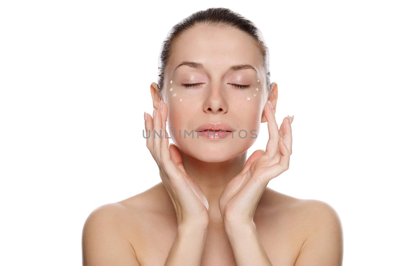 Beautiful sexy woman applying cosmetic cream on skin near eyes. Isolated on white background