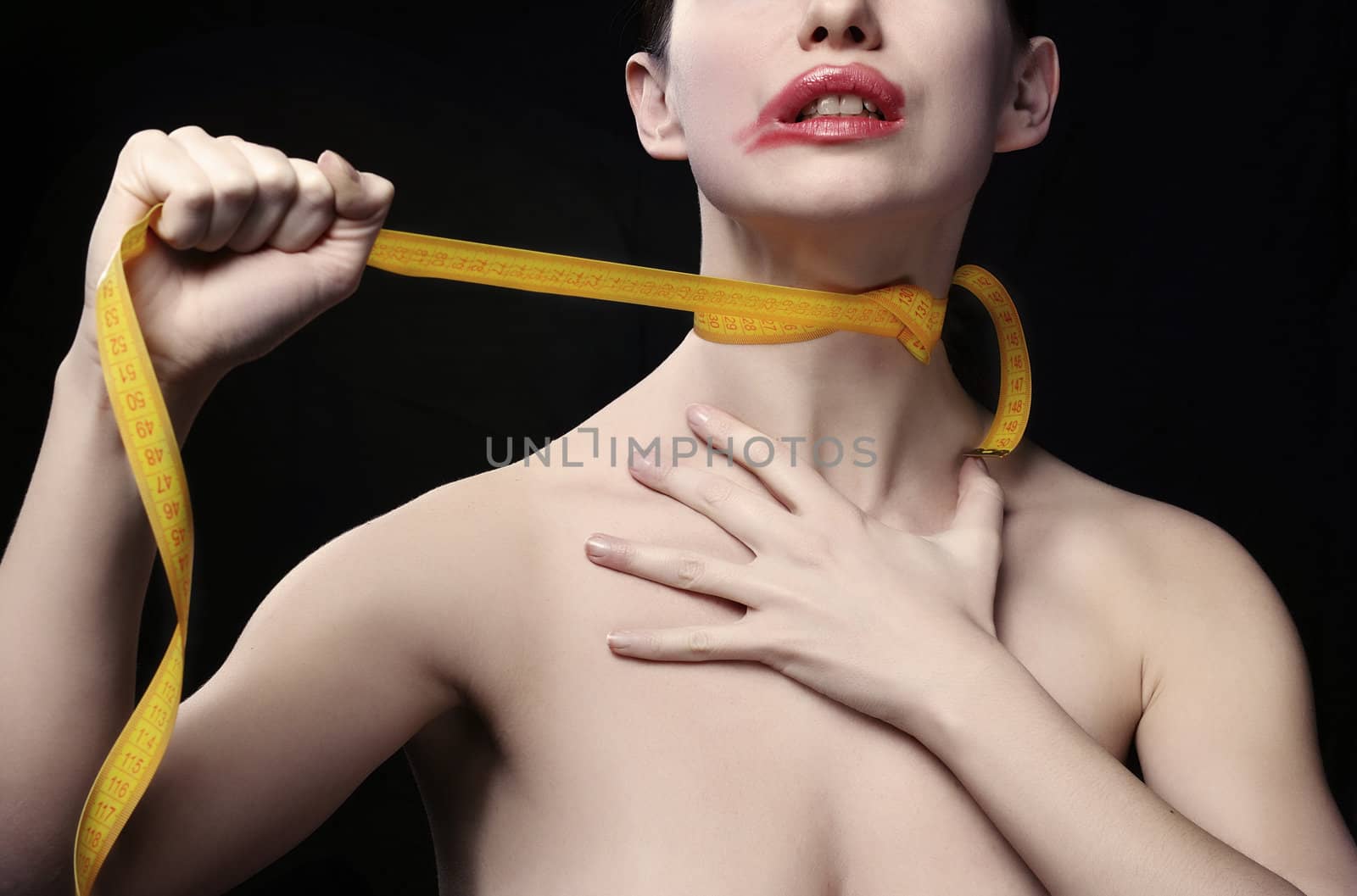 Young woman throttle herself by tape-line. Black background