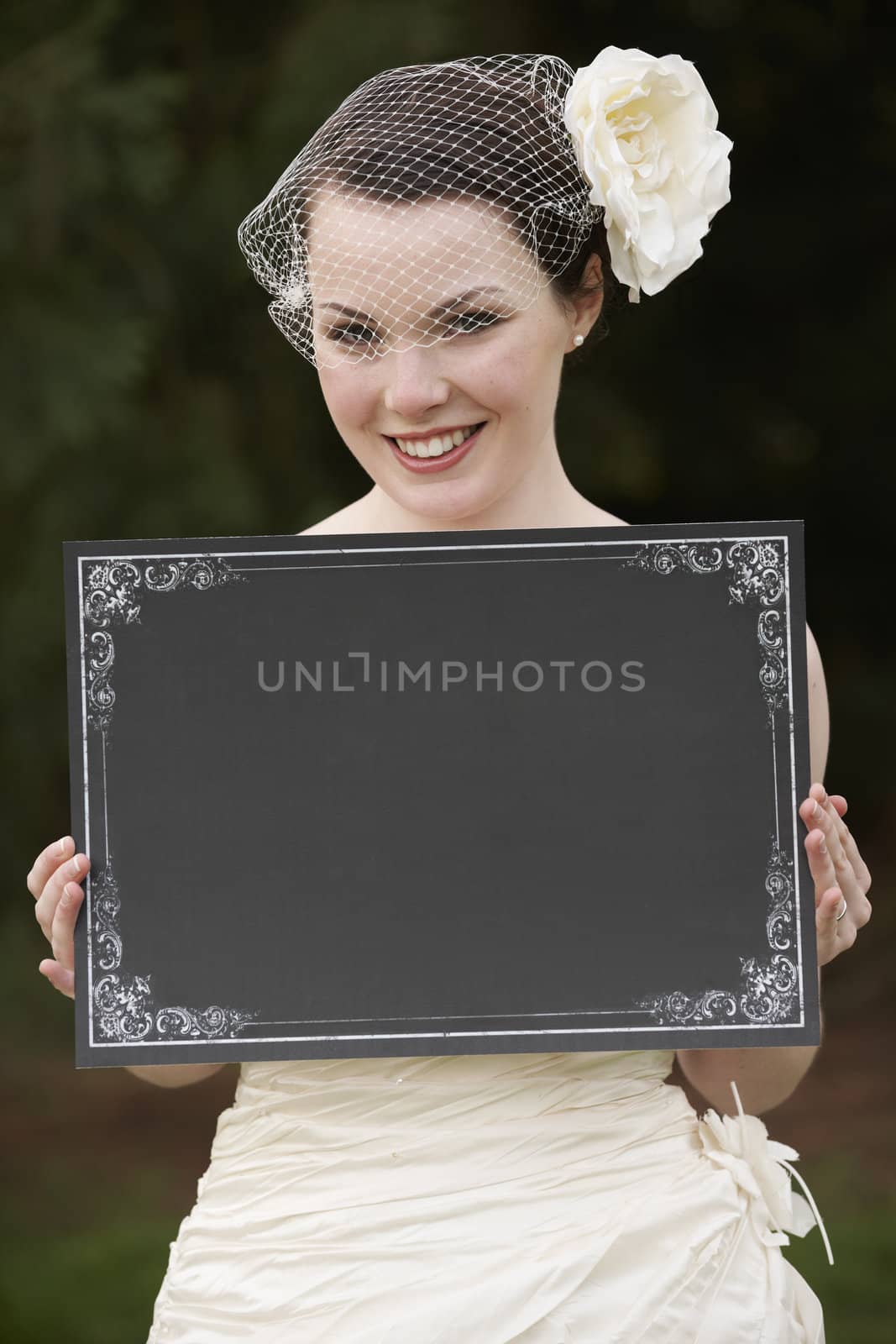 Pretty bride in wedding dress holding a blank board with space for copy