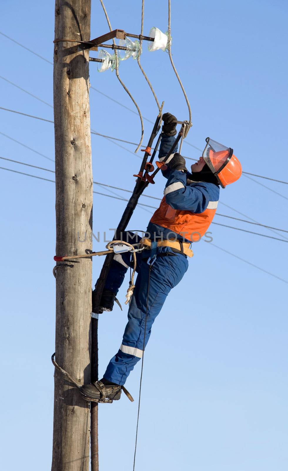 Electrician in blue overalls working at height