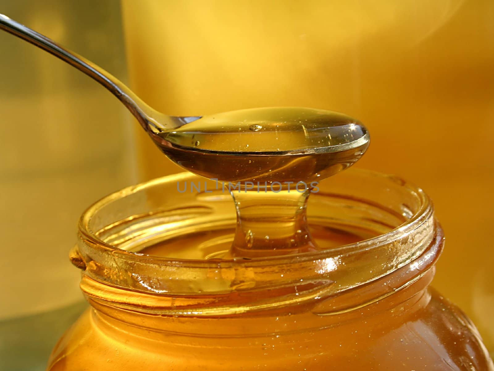 spoon scooping honey from jar by Baltus