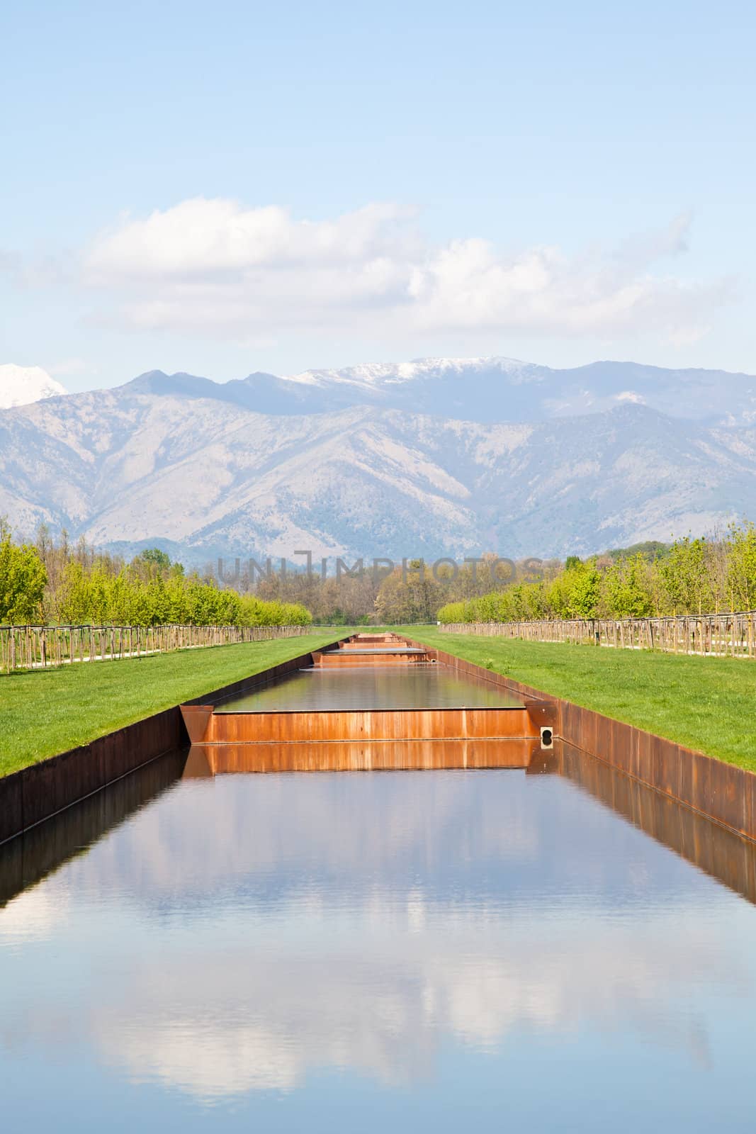 Italy - Water pool in green field with Alps mountains on background