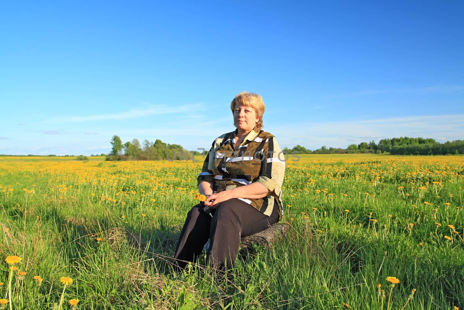 woman on stone amongst summer field