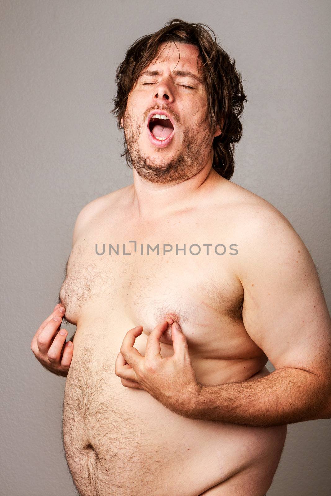 Funny picture of an overweight man pinching his own nipples while standing their nude