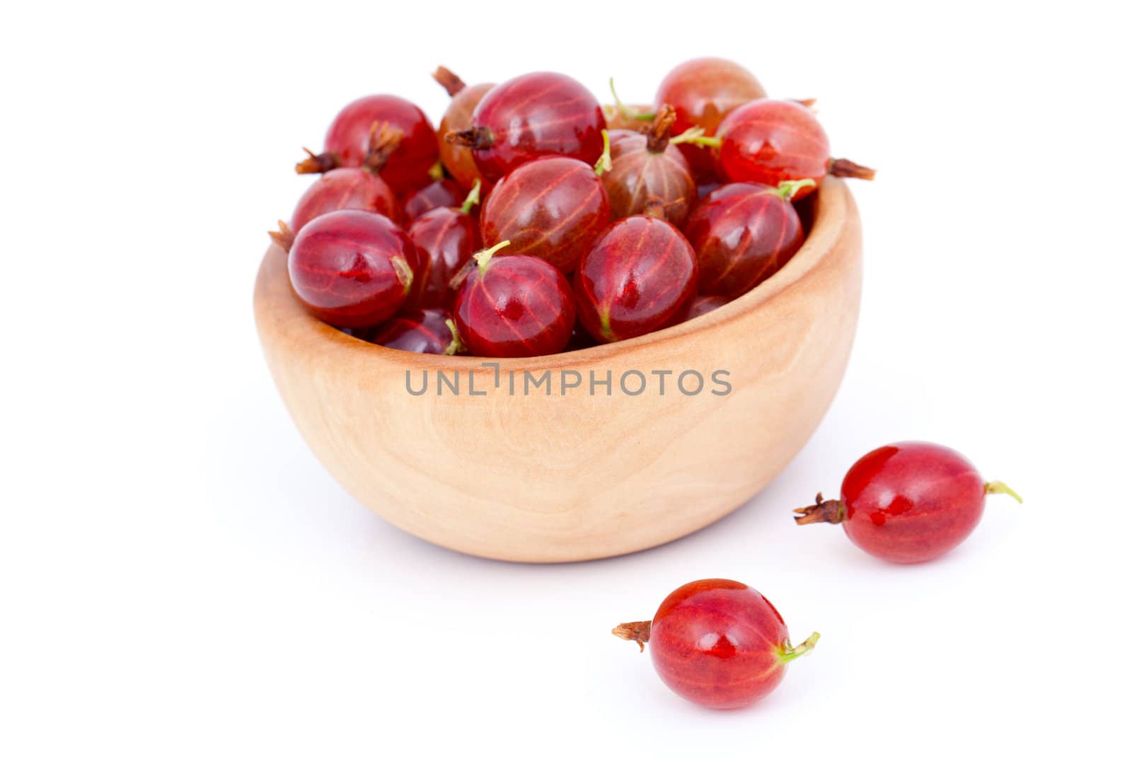 fresh red gooseberries in a wooden bowl, over a white background.