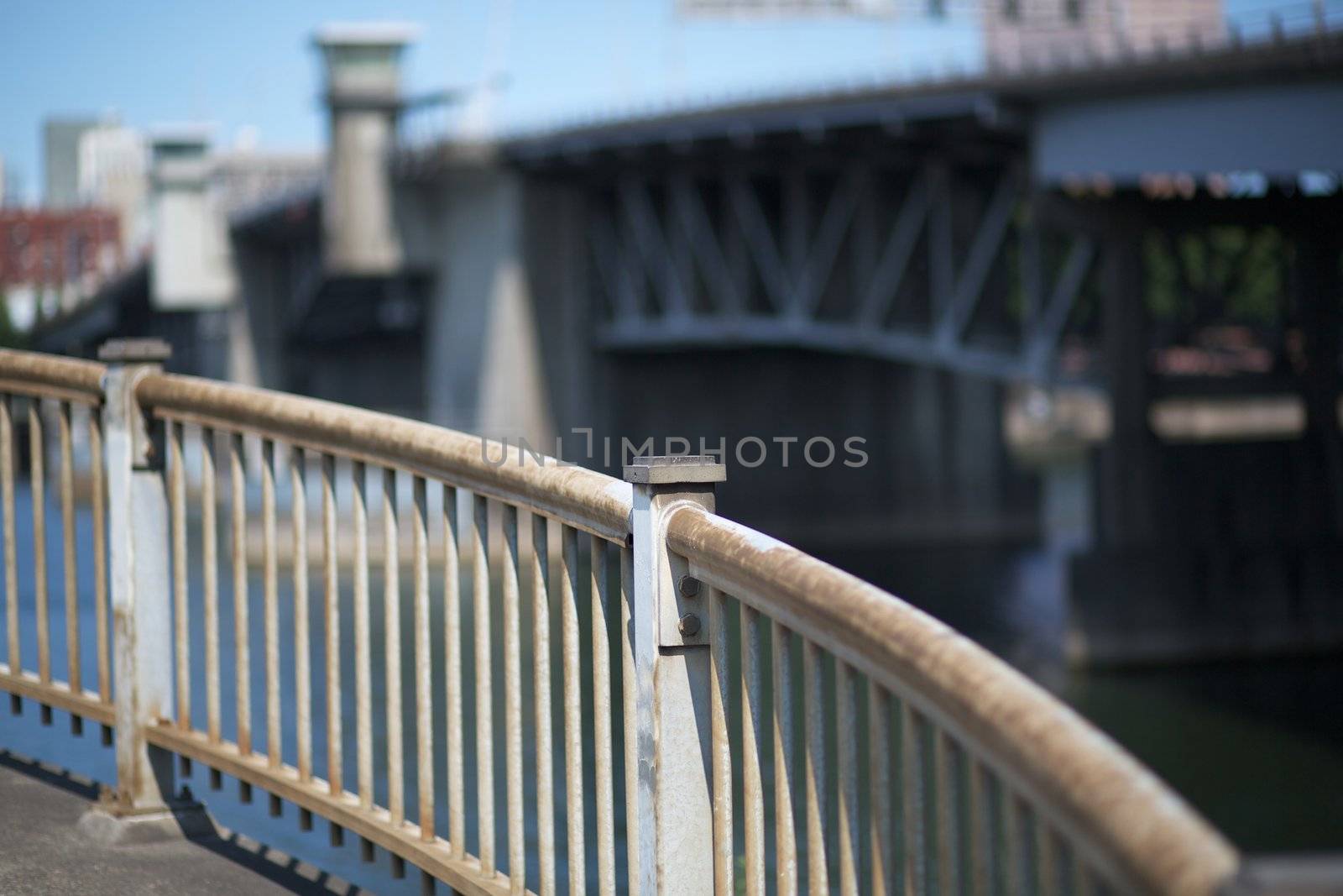 Curved steel railing with soft focus bridge and sky in Portland Oregon