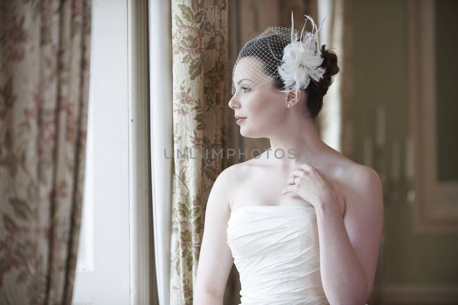 Pretty bride looking out of window and smiling on her wedding day