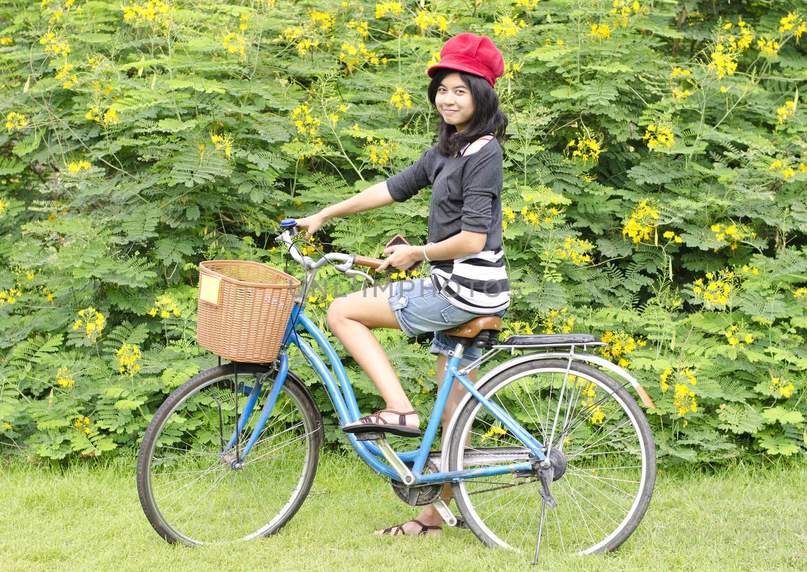 Pretty young woman with bicycle in a park smiling by siraanamwong
