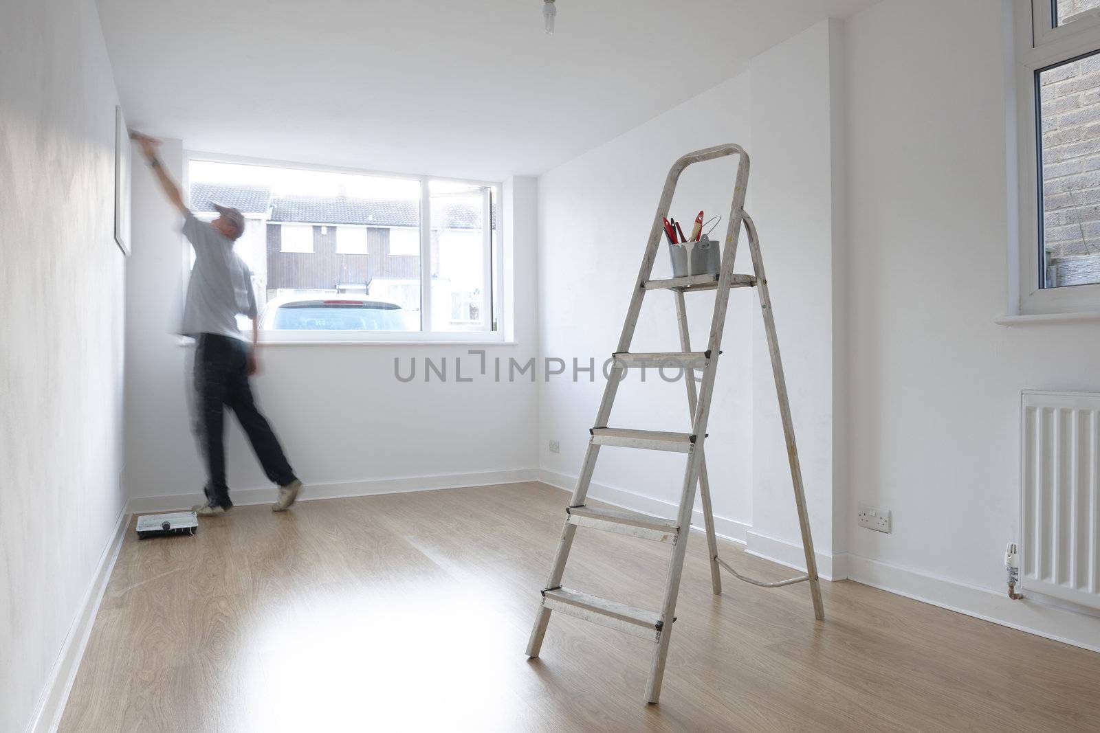 man decorating a room with ladder and paint pot in foreground