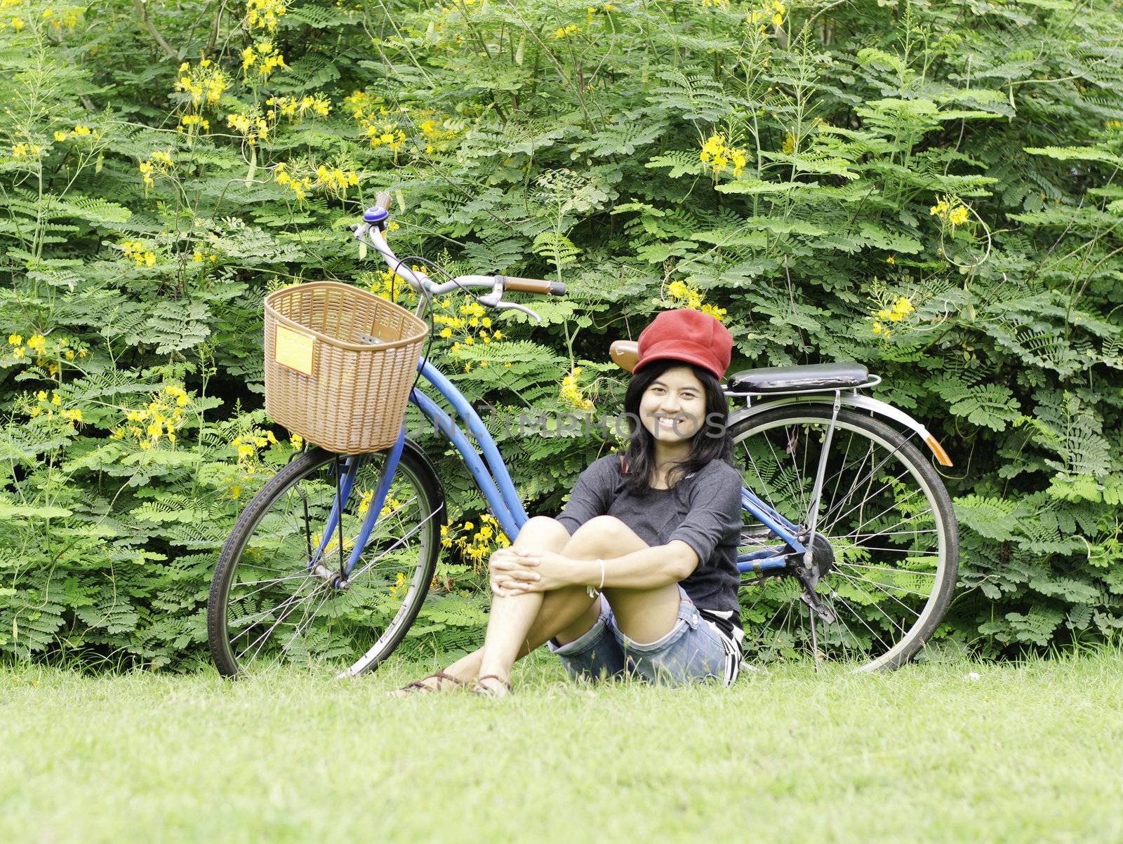 Girl with a bicycle rests on a grass by siraanamwong
