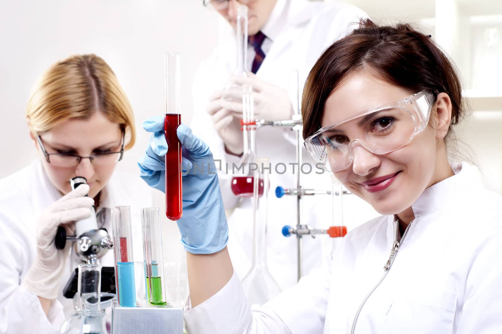 portrait of a beautiful woman chemist, looks at a test tube with red fluid