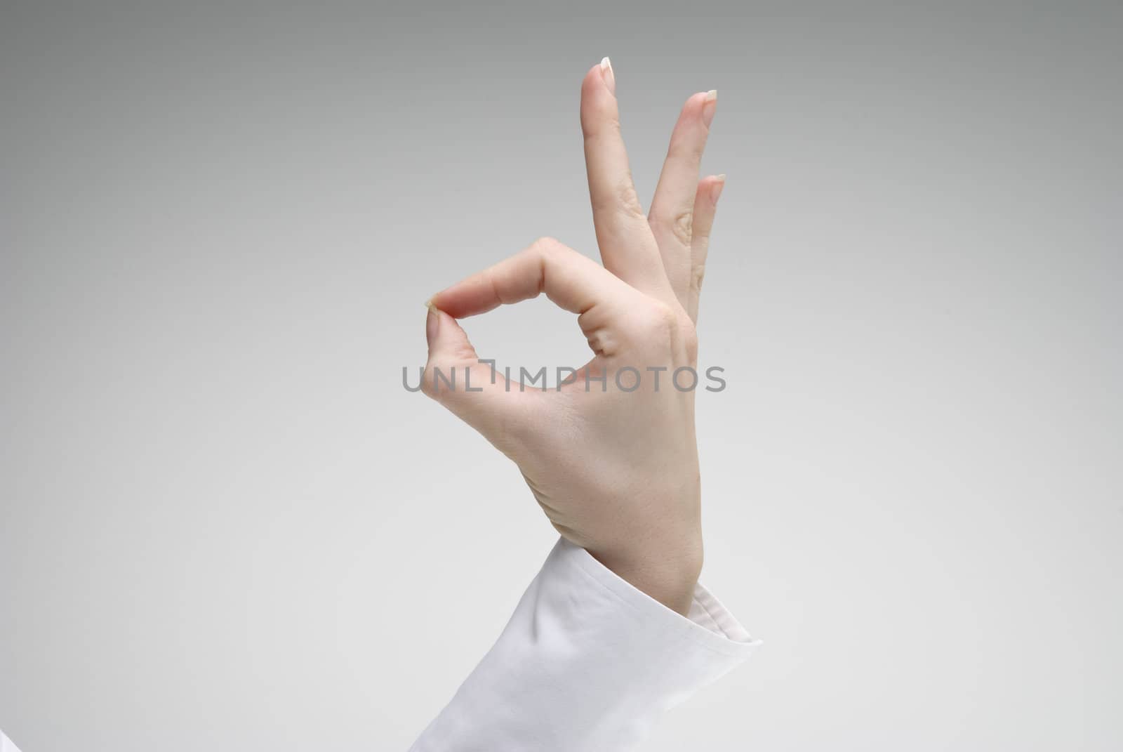 Woman's hand showing Ok symbol over light background
